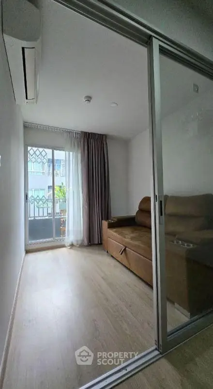 Cozy small living room with sliding glass doors and brown sofa, featuring natural light and modern design.