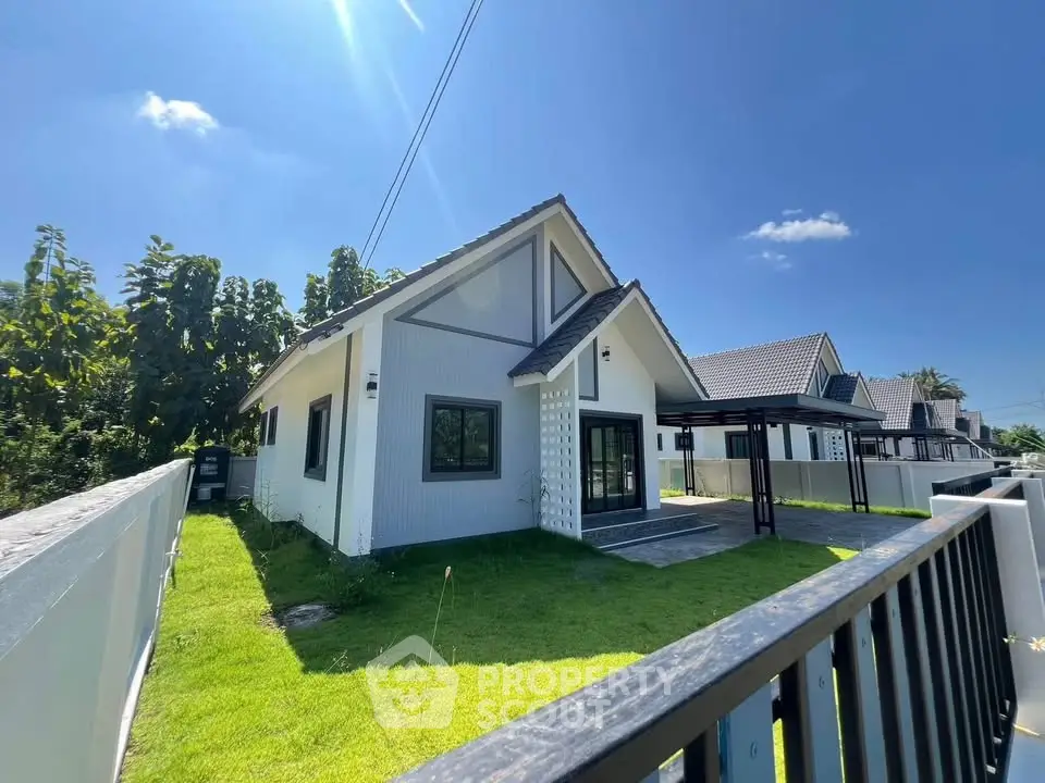 Charming modern house with lush green lawn and sleek design under a clear blue sky.
