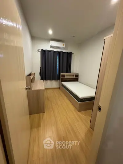 Cozy bedroom with wooden flooring and modern furniture, perfect for a comfortable living experience.