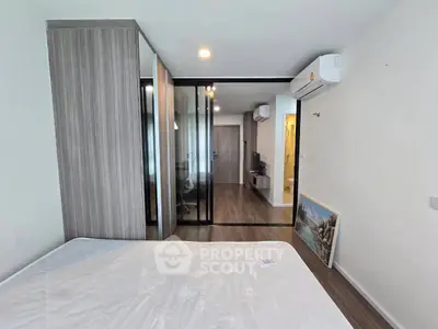 Modern bedroom with mirrored wardrobe and air conditioning in stylish apartment.
