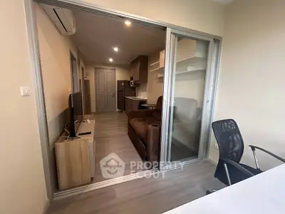 Modern apartment interior with sliding glass doors, cozy living area, and sleek kitchen design.