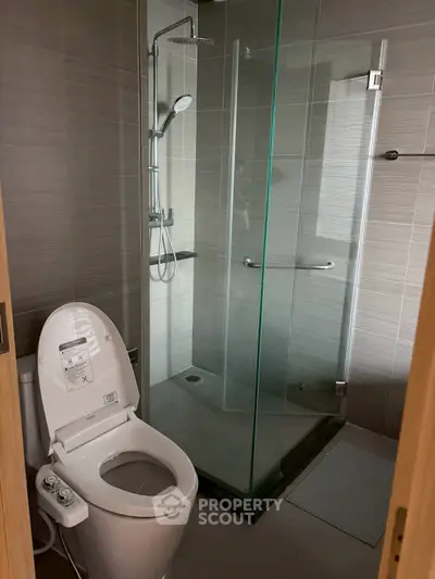 Modern bathroom with glass shower and smart toilet in sleek design.