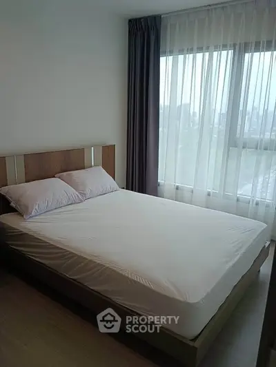 Modern bedroom with large window and stylish decor in a high-rise apartment.