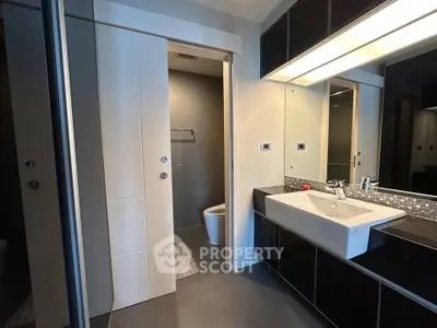 Modern bathroom with sleek design, featuring a large mirror, stylish sink, and contemporary fixtures.