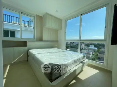 Bright bedroom with large windows offering stunning city views and ample natural light.