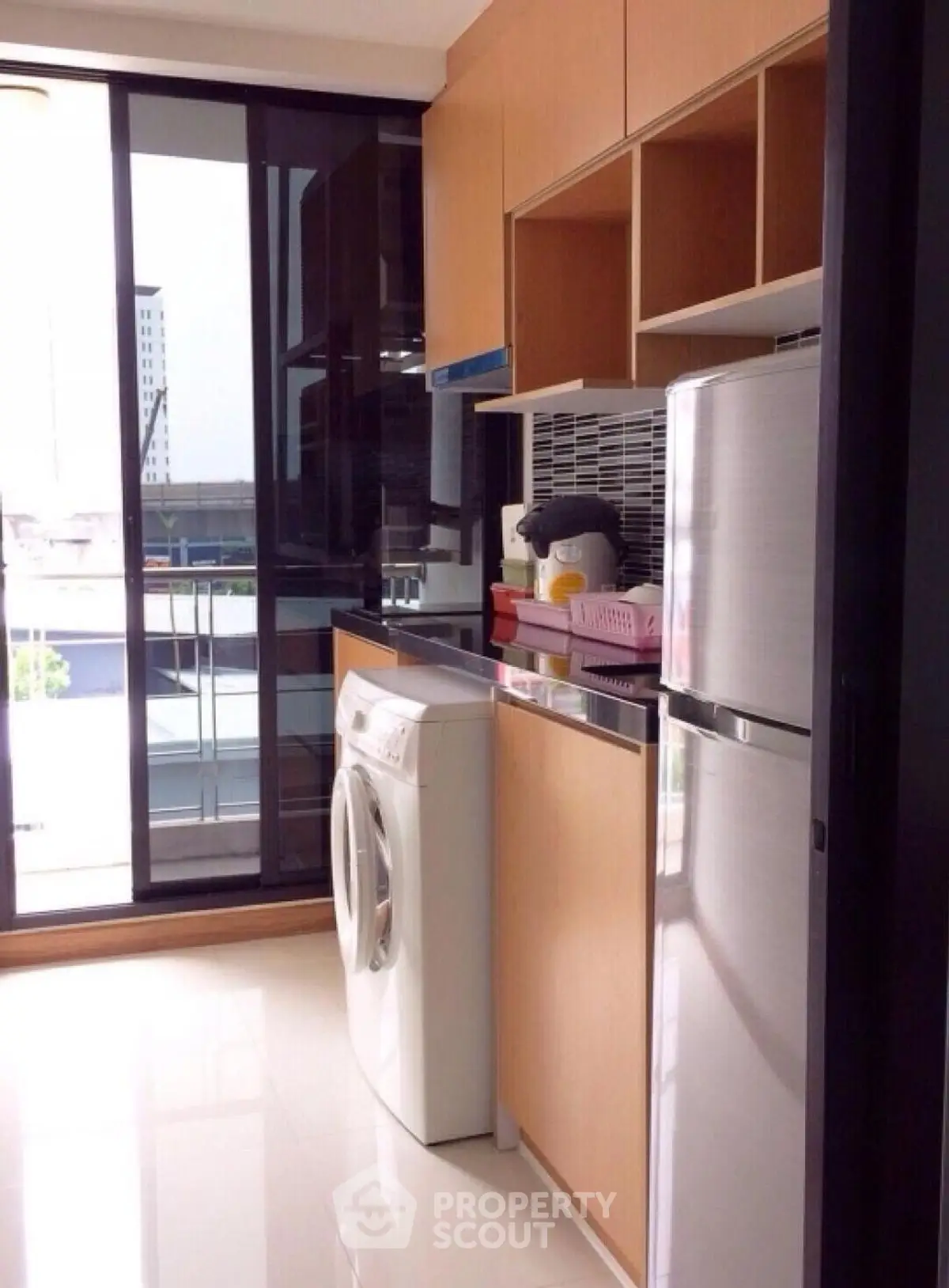 Modern kitchen with washing machine and stainless steel fridge in a bright apartment.
