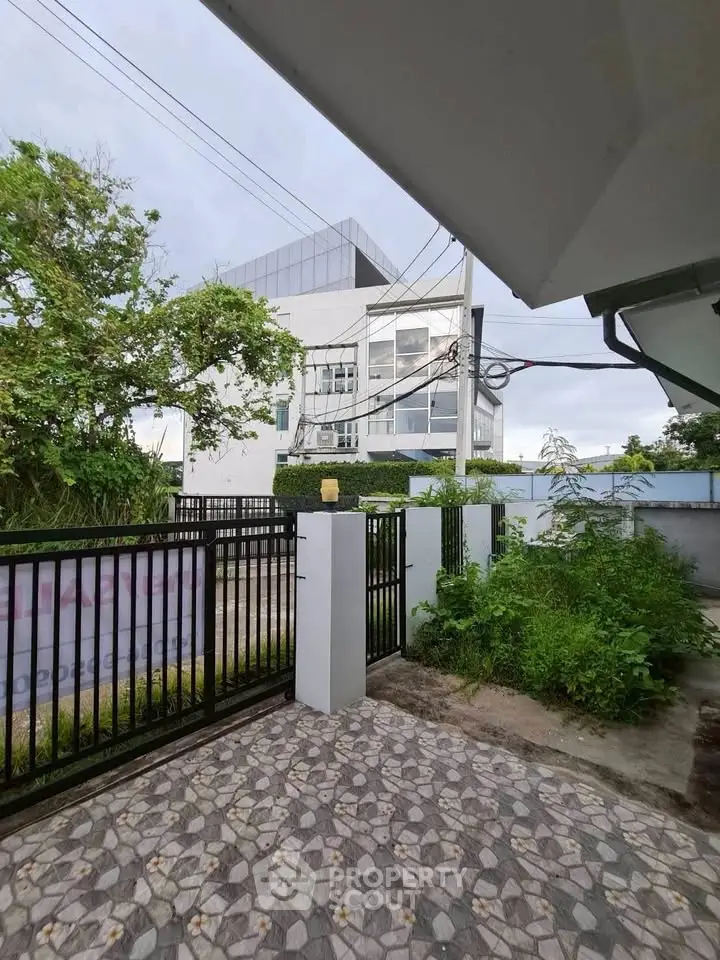 Modern building exterior with gated entrance and lush greenery, perfect for urban living.