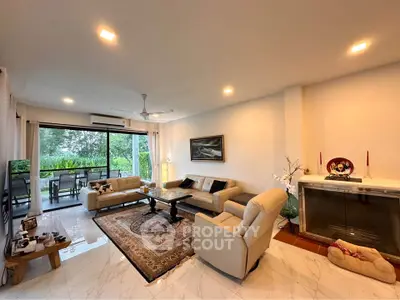 Spacious living room with elegant decor and large windows opening to a lush garden view.