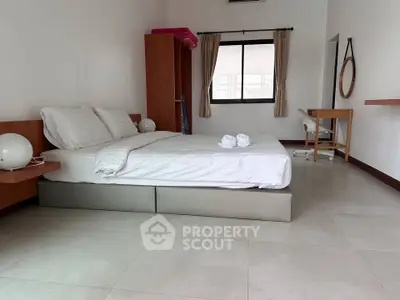 Spacious bedroom with modern furnishings and natural light, perfect for relaxation and comfort.