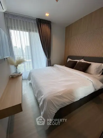 Modern bedroom with large window and stylish decor in a high-rise apartment.