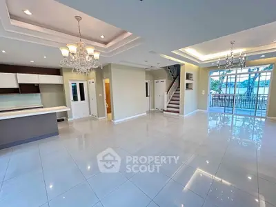 Spacious open-plan living area with elegant chandeliers and large windows.