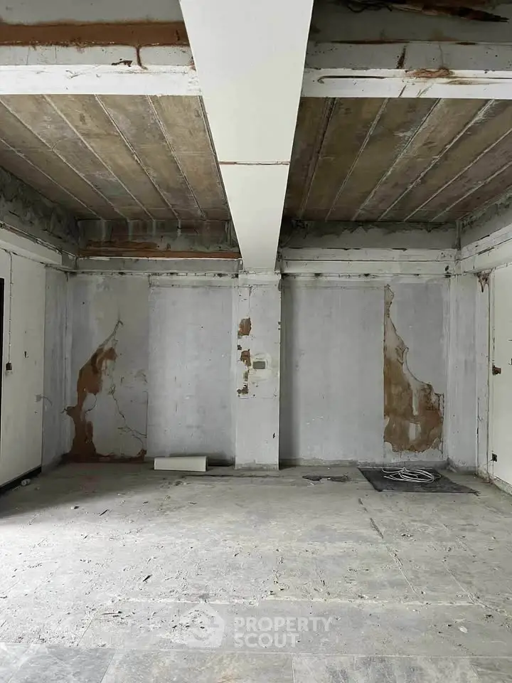 Spacious unfinished room with exposed concrete beams and walls, ideal for renovation projects.