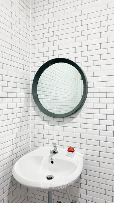 Modern bathroom with white subway tiles and round mirror above a sleek sink.