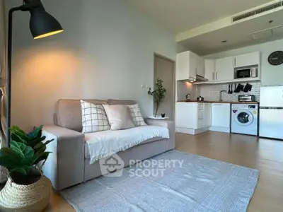Modern living room with cozy sofa and open kitchen featuring washing machine and oven.