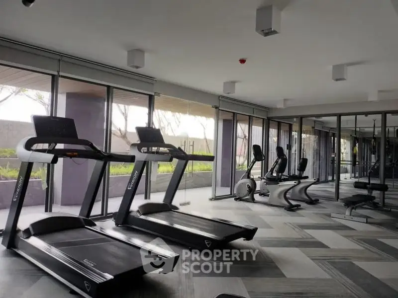 Modern gym with treadmills and exercise bikes in a luxury apartment complex.