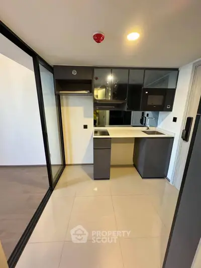 Modern compact kitchen with sleek cabinetry and built-in appliances in a contemporary apartment.