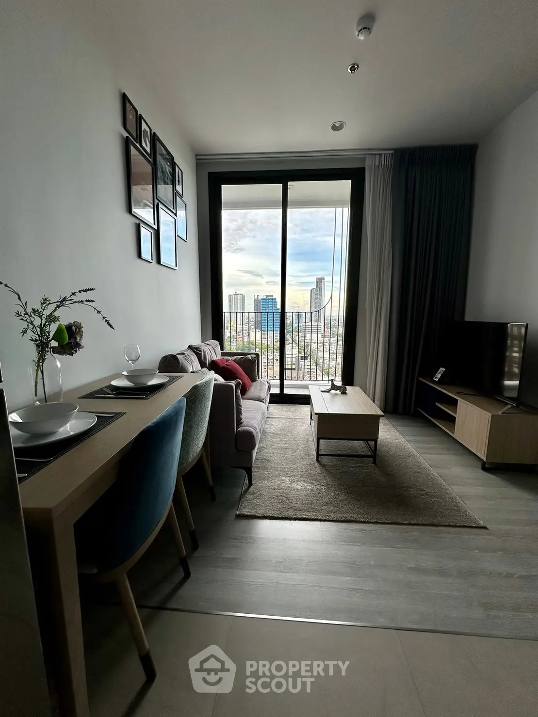 Modern living room with city view, stylish decor, and cozy seating area in a high-rise apartment.