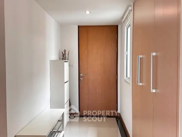 Modern apartment entrance with sleek wooden door and storage cabinets