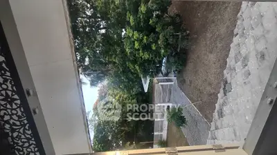 Charming garden view from a balcony with lush greenery and paved pathways.