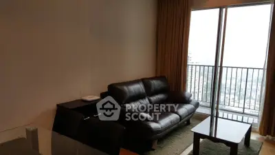 Modern living room with leather sofa and city view balcony in high-rise apartment.
