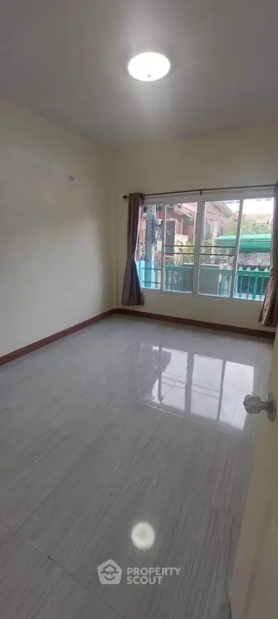 Spacious empty room with large window and tiled floor, perfect for customization.