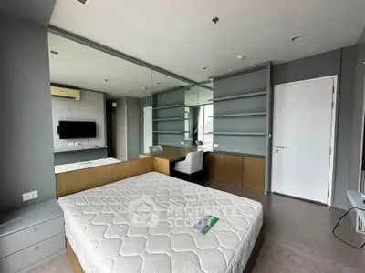 Modern bedroom with built-in shelves and large mirror, featuring a comfortable bed and sleek design.