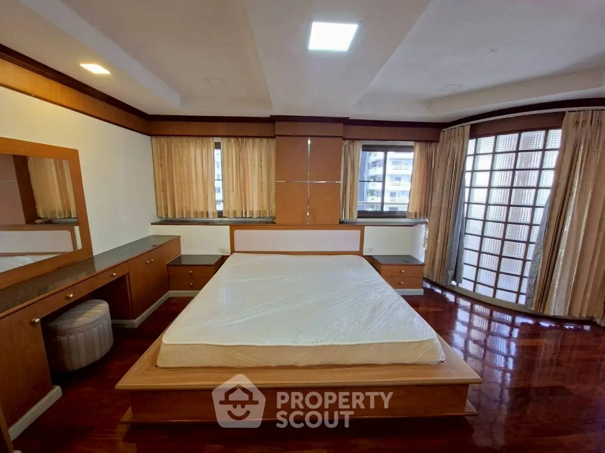 Spacious bedroom with wooden flooring and large windows in a modern apartment