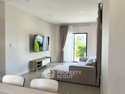 Modern living room with sleek furniture and large window offering garden view