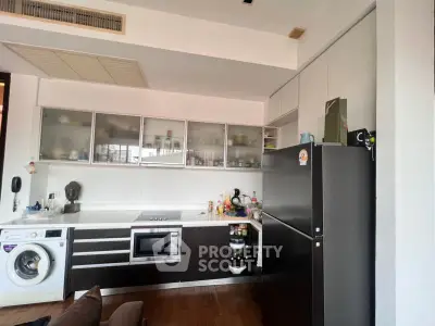 Modern kitchen with sleek cabinets, built-in appliances, and washing machine in stylish apartment.