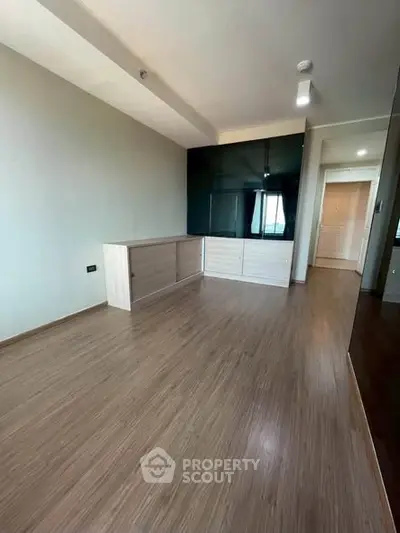 Spacious modern living room with sleek wooden flooring and built-in storage unit.