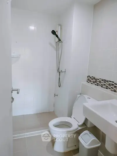 Modern bathroom with shower, toilet, and sink in a sleek, minimalist design.