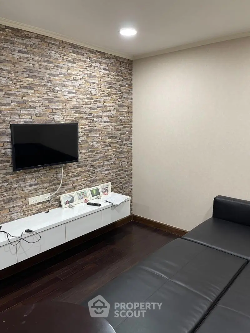 Modern living room with stone accent wall and sleek black sofa