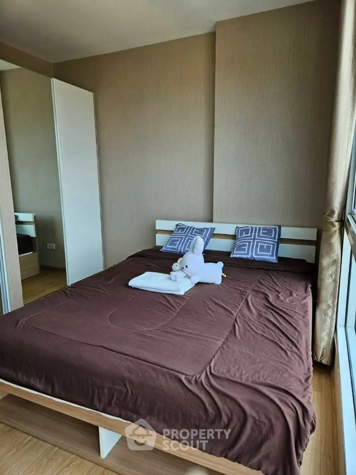 Cozy bedroom with modern decor and large window offering natural light.