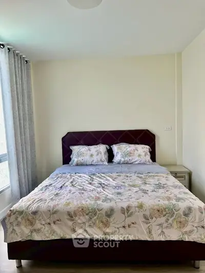 Cozy bedroom with floral bedding and natural light, perfect for relaxation.