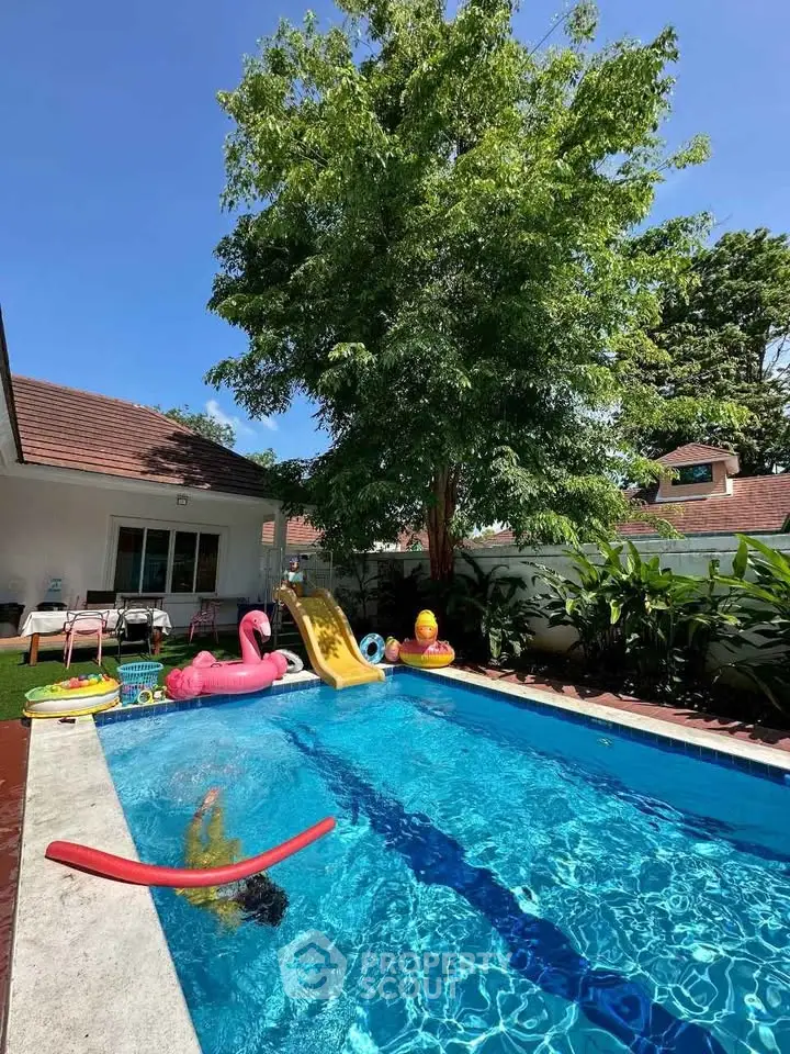 Charming backyard with a sparkling pool, lush greenery, and playful inflatables, perfect for family fun and relaxation.