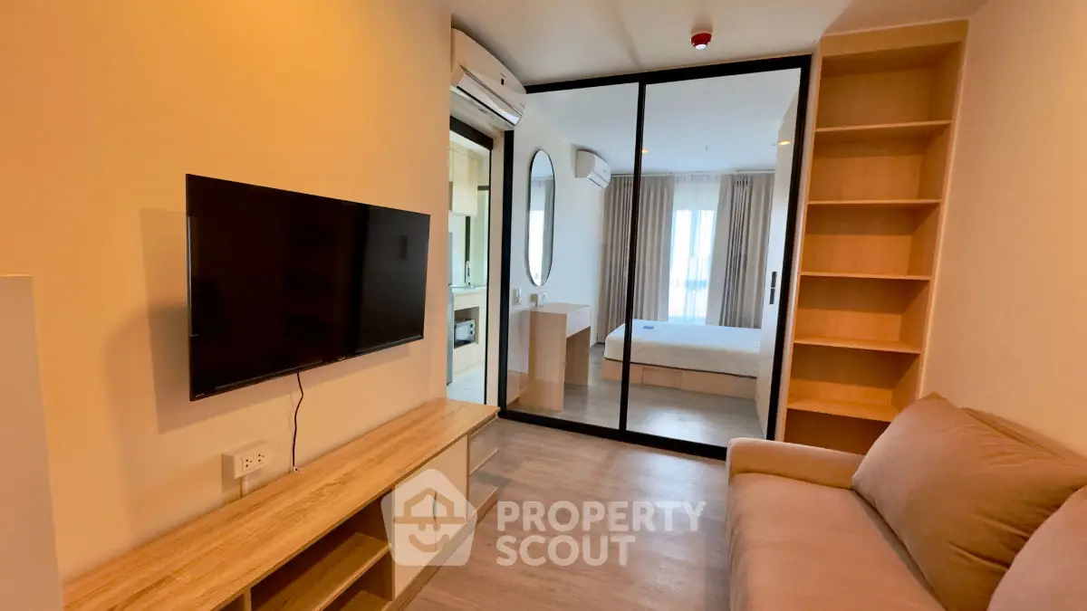 Modern apartment with open living room and bedroom, featuring sleek design and natural light.