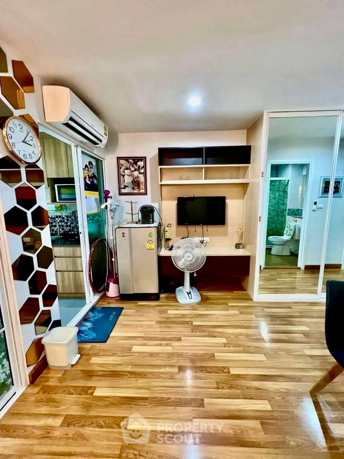 Modern living room with wooden flooring, air conditioning, and stylish decor.