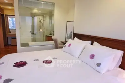 Luxurious bedroom with ensuite bathroom featuring a glass shower and elegant decor.