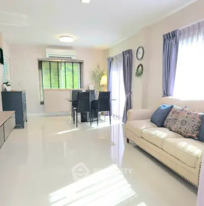 Spacious living room with elegant decor and natural light, featuring a cozy sofa and dining area.