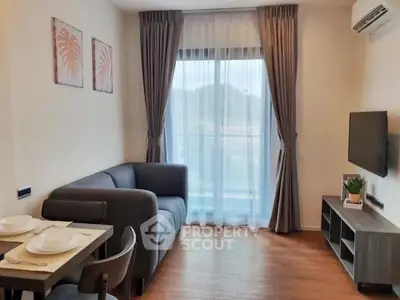 Modern living room with cozy gray sofa and dining area, featuring elegant curtains and wall art.