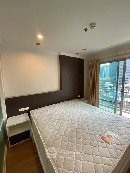Spacious bedroom with large window and city view, featuring a comfortable bed and modern design.