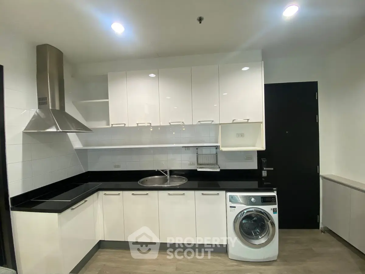 Modern kitchen with sleek white cabinets and built-in washing machine