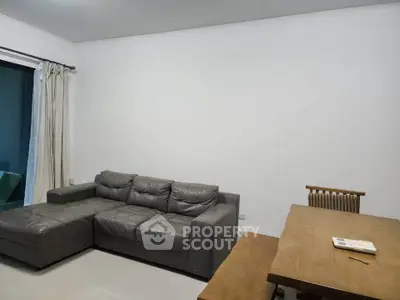 Spacious living room with modern gray sectional sofa and wooden dining table, perfect for family gatherings.
