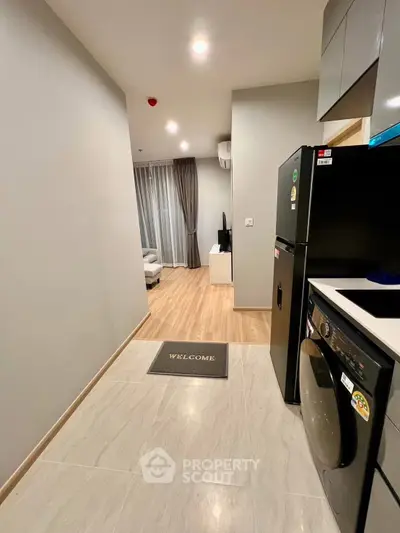 Modern apartment interior with kitchen and living area, featuring sleek appliances and stylish decor.