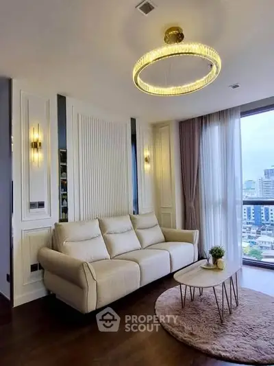 Elegant living room with modern chandelier and city view, featuring a cozy sofa and stylish decor.