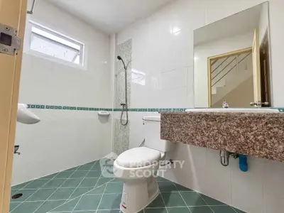 Modern bathroom with sleek design and tiled flooring, featuring a shower and large mirror.