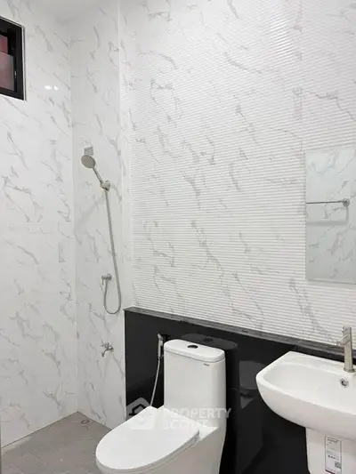 Modern bathroom with sleek fixtures and marble-style tiles, featuring a shower and toilet.