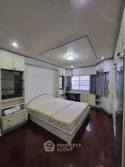 Spacious bedroom with elegant built-in storage and large windows for natural light.
