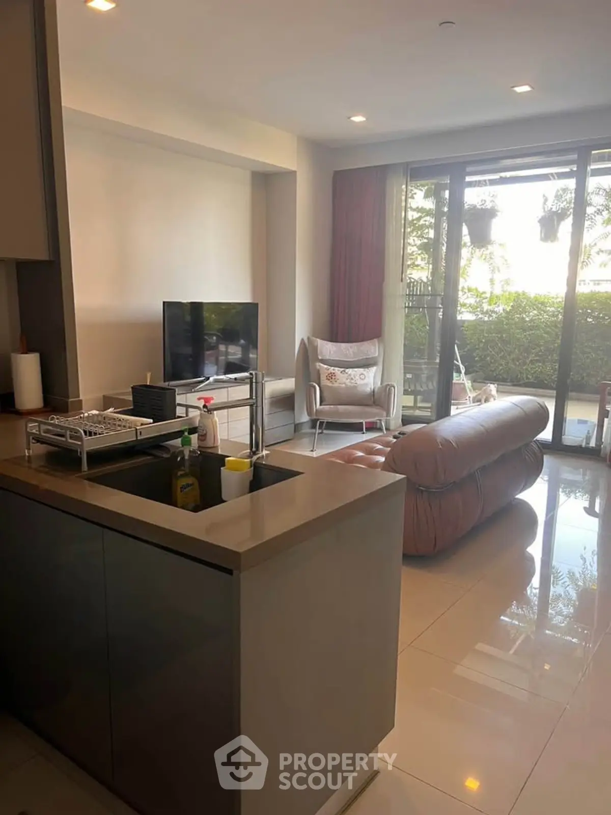 Modern living room with open layout and garden view, featuring sleek furniture and natural light.