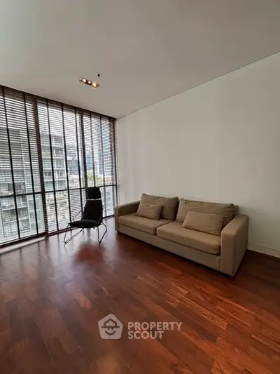 Spacious living room with modern furniture and large windows offering city views.